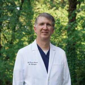 Dr. Shakespear in whitecoat and scrubs with forest background