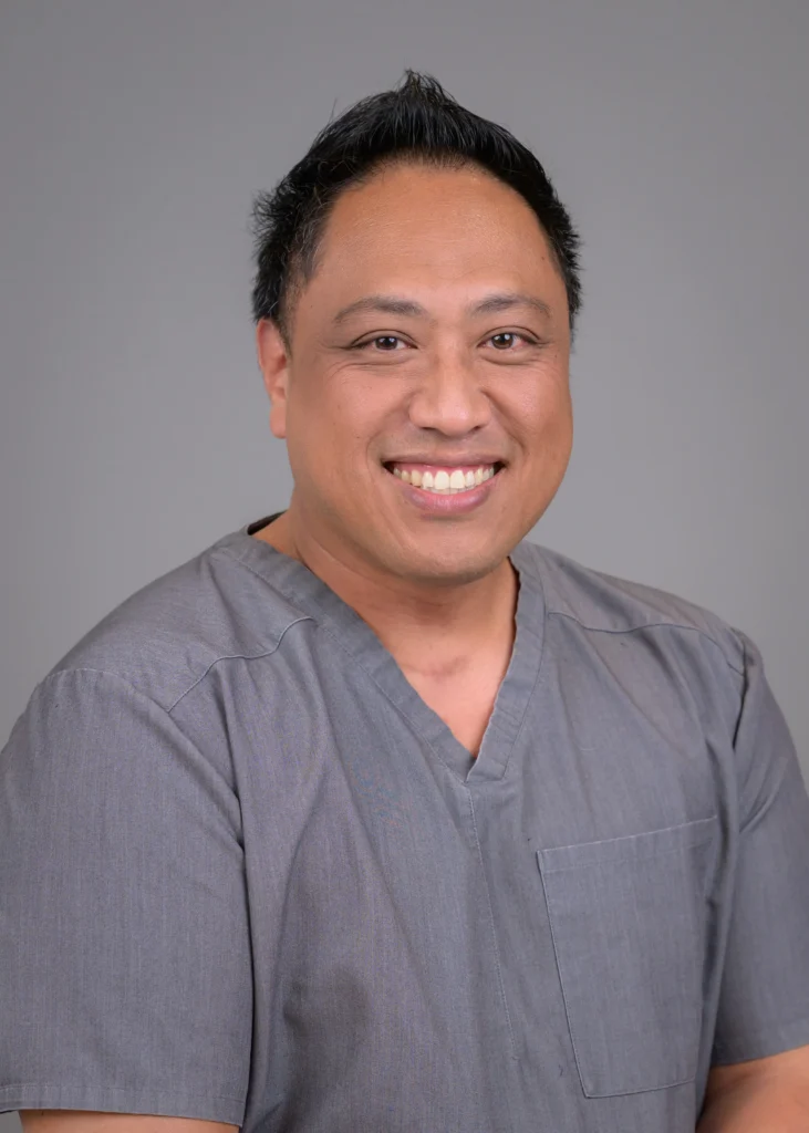 Dr. Ioane Ofisa in grey scrubs.