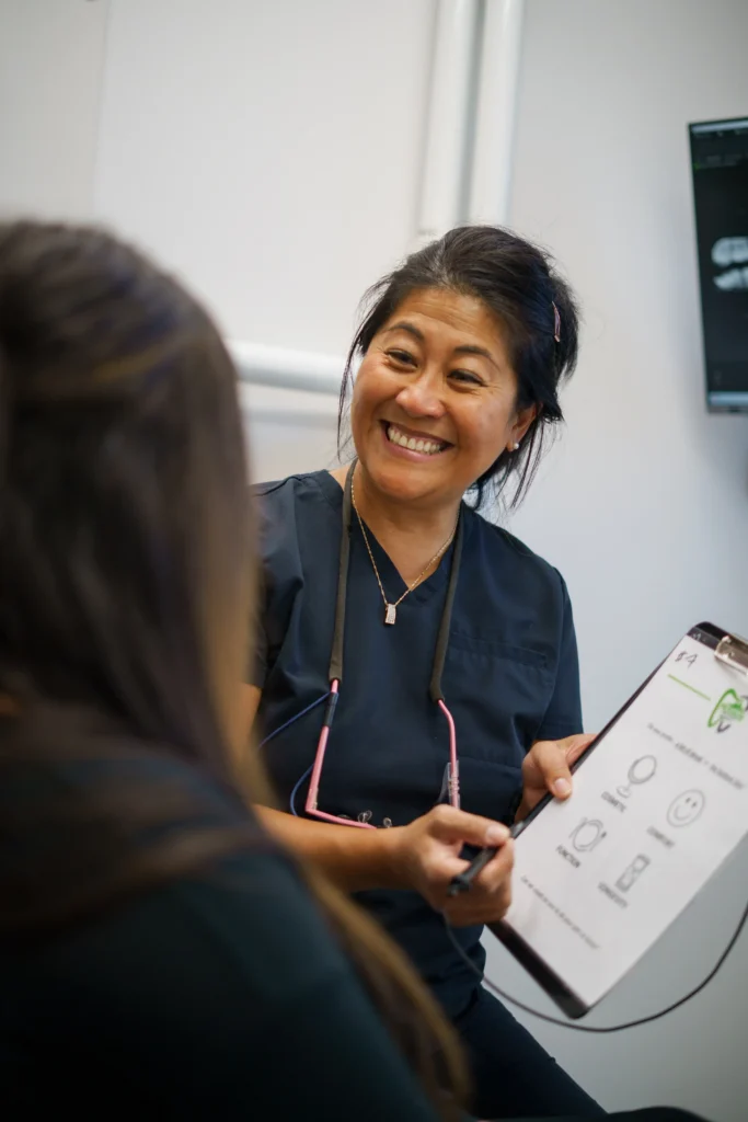 Springfield Dental Hygienist smiling at patient while holding up a clipboard and dental information sheet